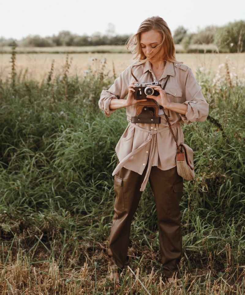 a-young-woman-stands-in-the-grass-with-a-camera